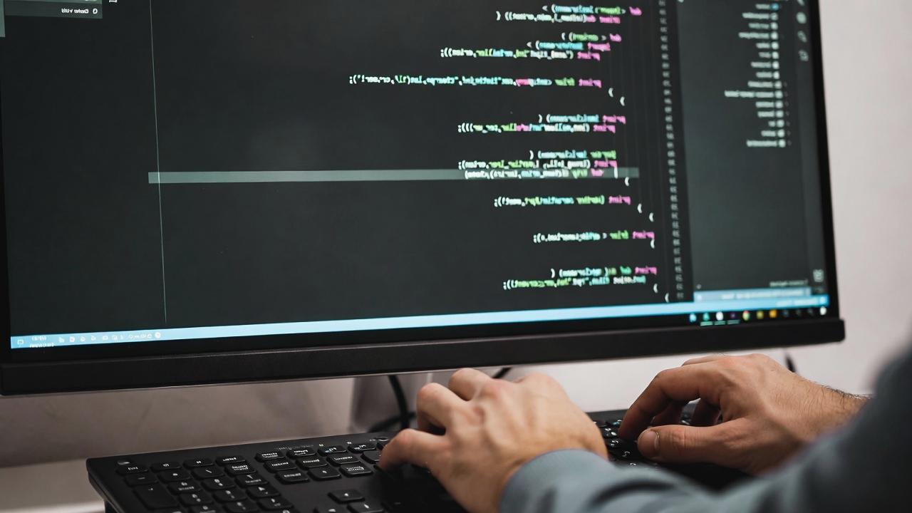 デスクで肩を押さえながらキーボード作業をする人物のイメージ