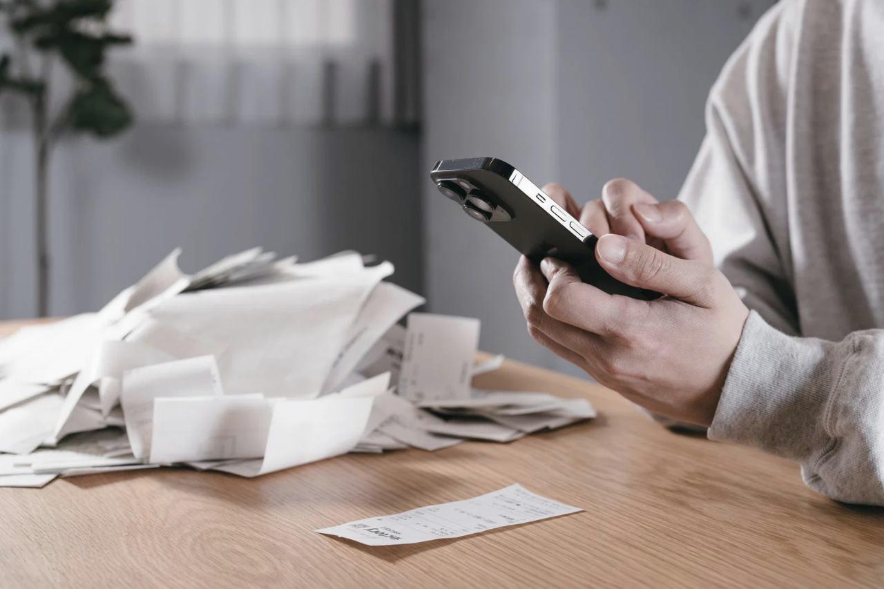 すっきりと整理されたポーチと共に、スマートフォンを手に取る落ち着いた人物の後ろ姿